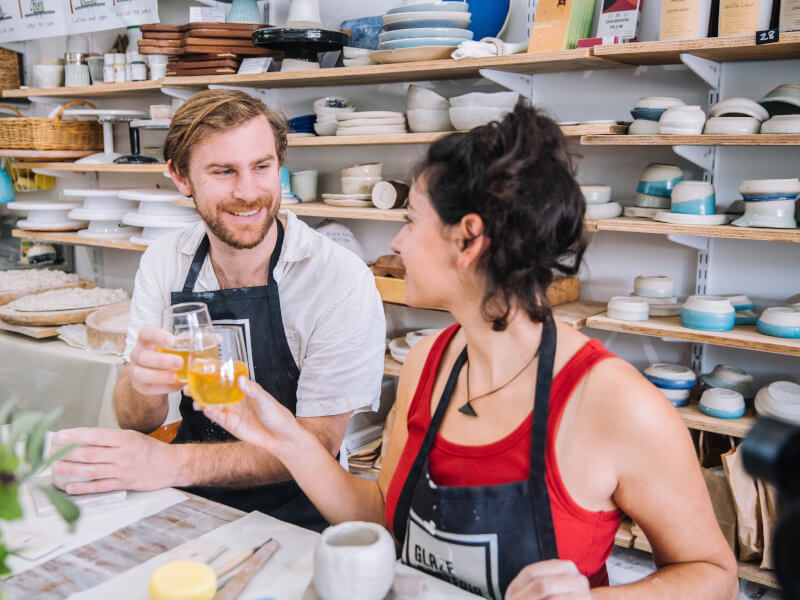Two people cheersing their glasses in a clay and sip class